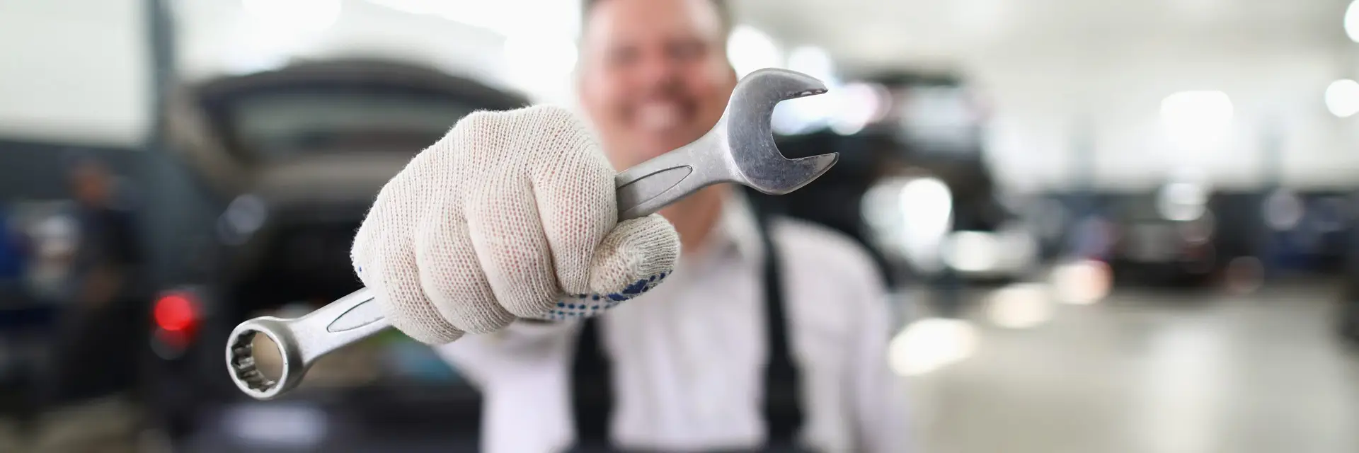 Male repairman holding wrench in car workshop closeup