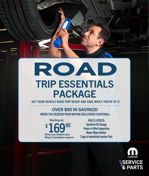 Mopar technician performing under-vehicle inspection for Road Trip Essentials Package promotion
